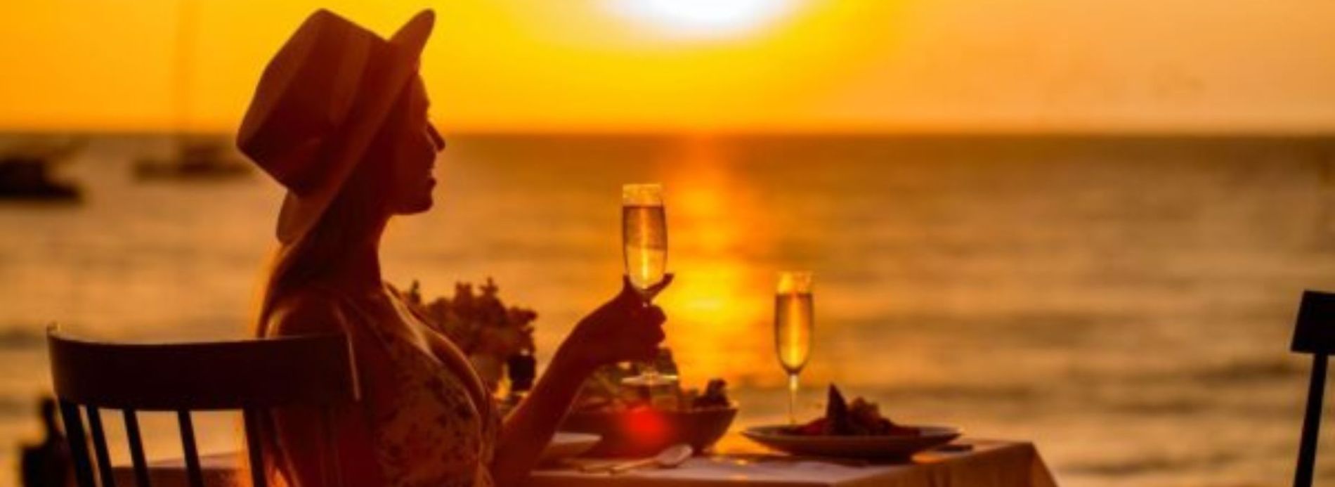 woman dining by water at sunset