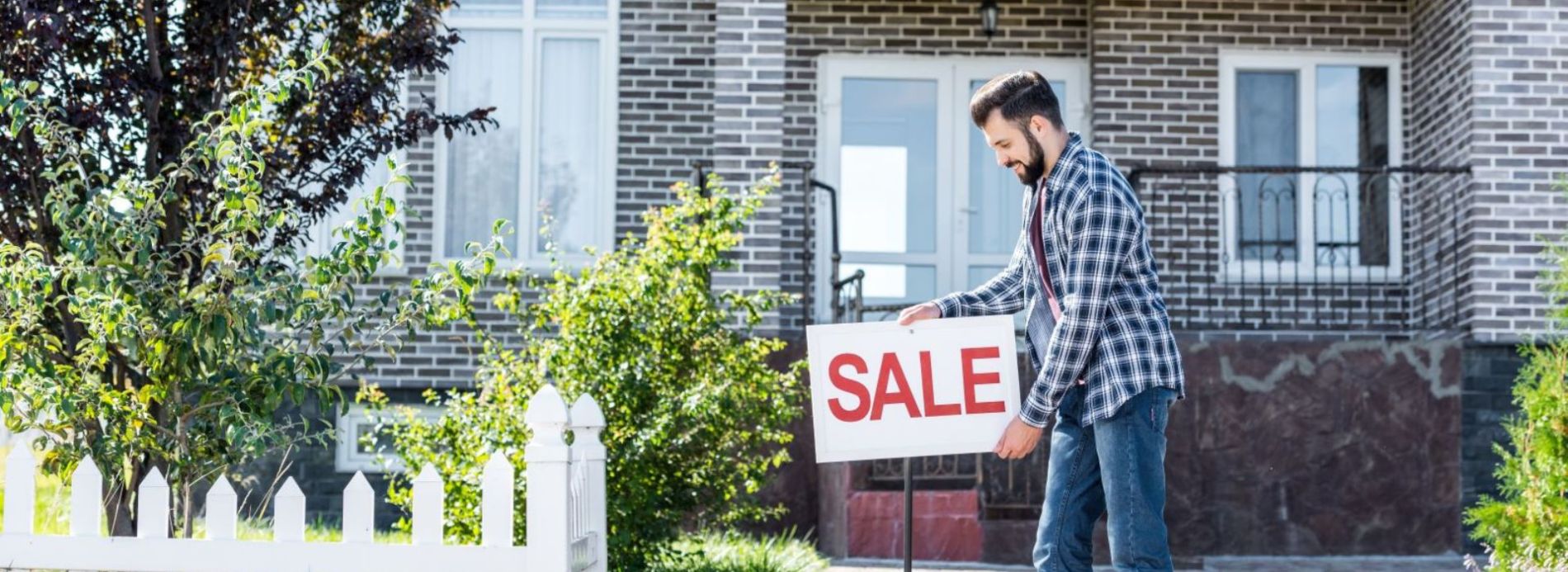Man putting up for sale sign